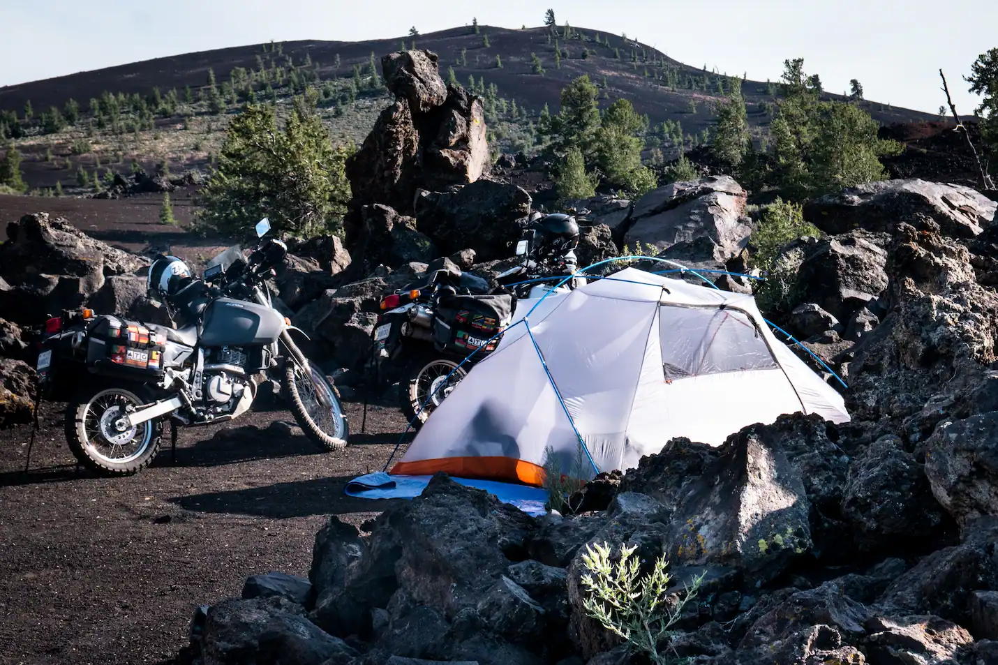 Setting up a lightweight Sea to Summit tent beside loaded adventure motorcycles during an overland trip. Lightweight freestanding tents are well suited to motorcycle camping where packed size, weight, weather protection and easy setup matter.